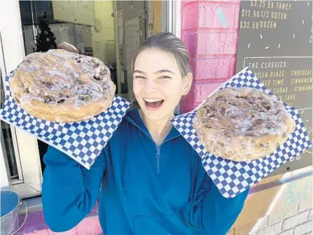  ?? DG DOUGHNUTS ?? DG employee Sarah Jane Caudill shows off fritters “as big as your face” in front of the Oakland shop. Come January, DG Doughnuts will be moving to a larger location in Ocoee.