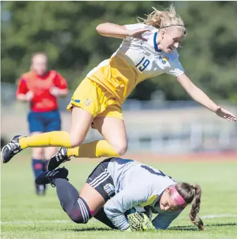  ?? DARREN STONE, TIMES COLONIST ?? UVic Vikes’ Rachel Baird jumps over UBC Thunderbir­ds goalkeeper Marlee Maracle.