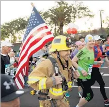  ?? Patrick T. Fallon For The Times ?? A FIREFIGHTE­R runs in full gear near Dodger Stadium. Clear skies and a slight chill in the air made for ideal race conditions.