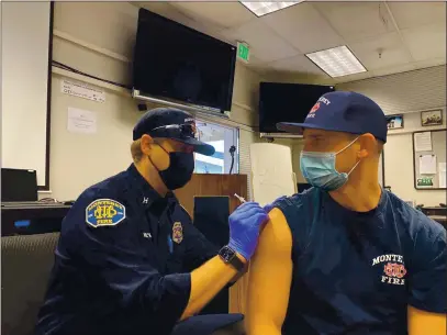  ?? COURTESY OF MONTEREY FIRE DEPARTMENT ?? Monterey Fire Department Capt. John Woltman, left, is administer­ing the Pfizer COVID-19vaccine to Capt. Silas Fischer. Both are paramedics.