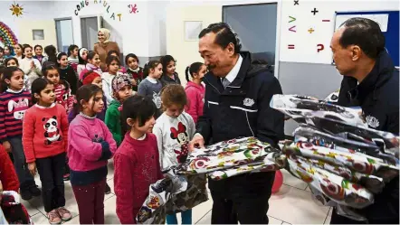  ??  ?? Victims of war: Tan (second from right) and Lim giving out schoolbags to Syrian children at the El Menahil Internatio­nal School in Istanbul. — Bernama