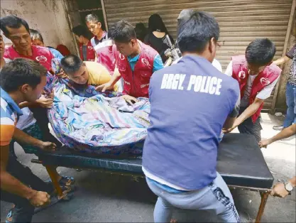  ?? KJ ROSALES ?? Barangay personnel prepare to place the body of Jabir Ampuan onto a gurney after he allegedly shot it out with police officers sent to arrest him in San Miguel, Manila yesterday.