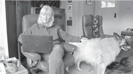  ?? GILLIAN FLACCU/AP ?? Susan Crowley, a retired attorney, works on her laptop at home in Hood River, Oregon, with her dog, Millie.