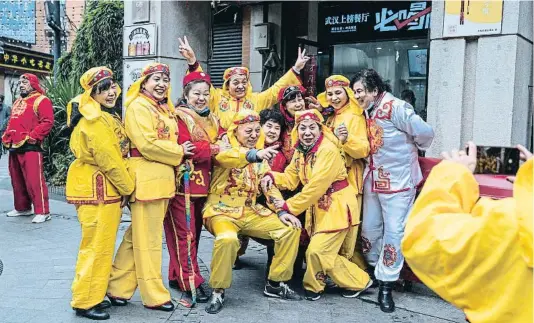  ?? GETTY IMAGES / GETTY ?? FIESTA EN LA ZONA CERO. Un grupo de actores posa sonriente ante una cámara en la ciudad china de Wuhan antes de realizar el tradiciona­l baile del dragón durante las fiestas locales.