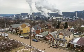  ?? Andrew Rush/Post-Gazette ?? Plumes rise from U.S. Steel’s Clairton Coke Works behind homes in Clairton in 2019. U.S. Steel has announced plans to reach net-zero emissions by 2050.