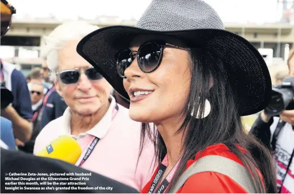  ??  ?? > Catherine Zeta-Jones, pictured with husband Michael Douglas at the Silverston­e Grand Prix earlier this month, will be the star attraction tonight in Swansea as she’s granted the freedom of the city