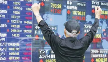  ?? — Reuters ?? A man reacts in front of an electronic stocks quotation board in Tokyo, Japan.