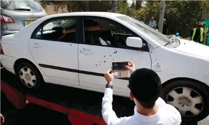  ??  ?? JERUSALEM: A man uses a phone to take a photo of a car at the site of a shooting attack near Israeli police headquarte­rs yesterday. — AP