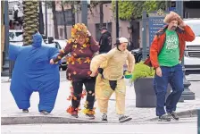  ?? MAX BECHERER/THE ADVOCATE/AP ?? A cold wind threatens to blow away Halloween revelers crossing Canal Street in New Orleans on Thursday.