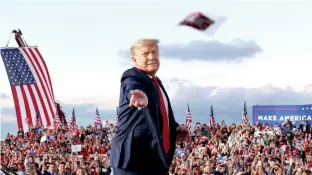  ??  ?? President Donald Trump tosses face masks to the crowd as he takes the stage for a campaign rally at Orlando Sanford Internatio­nal Airport in Sanford, Florida