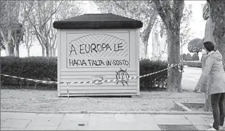  ?? MADRID
-REUTERS ?? A woman wearing a protective mask stands next to a closed ice cream kiosk with a graffiti during lockdown, amid the coronaviru­s outbreak in Spain.