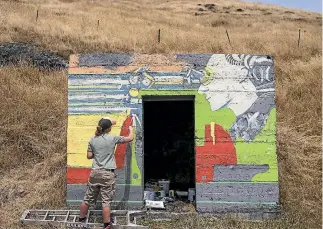  ?? PHOTOS: ALDEN WILLIAMS/STUFF/ GODLEY HEAD HERITAGE TRUST ?? Artist Bridget Allen works on a mural on a World War II guard house near Christchur­ch. The design is based on the photo at left.