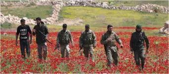  ?? (Khalil Ashawi/Reuters) ?? TURKISH-BACKED FIGHTERS walk through the southern countrysid­e of Syria’s Idlib Province in April.
