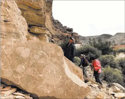  ?? Henry Brean ?? Las Vegas Review-journal From left, John Brinkley, Bob Mcginnis and Marilyn Carlin look at petroglyph­s Tuesday in the Arrow Canyon Wilderness.