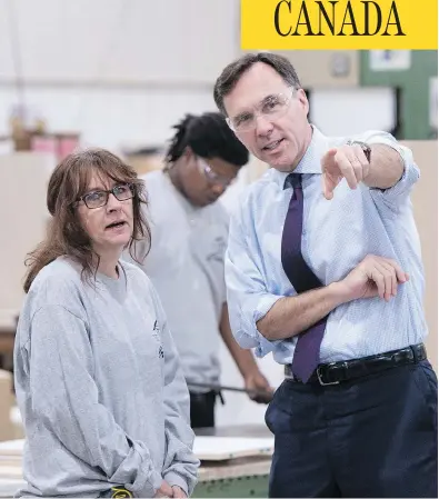  ?? PAUL CHIASSON / THE CANADIAN PRESS ?? Finance Minister Bill Morneau visits with a worker at a kitchen counter factory in Montreal on Tuesday.