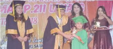  ??  ?? Zamri (second left) hands over a certificat­e to a pre-schooler while Napsiah (left) and Bangi look on.