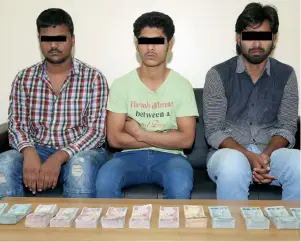  ?? Supplied photo ?? The three suspects in custody of RAK Police with the Dh287,000 they robbed. —