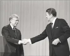  ?? Madeline Drexler / Associated Press ?? In this Oct. 28, 1980 file photo, President Jimmy Carter shakes hands with Republican Presidenti­al candidate Ronald Reagan after debating in the Cleveland Music Hall in Cleveland.