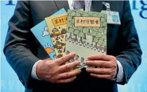  ?? AP ?? Police superinten­dent Li Kwai-wah with the three children’s books authoritie­s claim would incite hatred and violence and encourage disobedien­ce of the law.