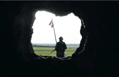  ?? Picture: AFP ?? ON GUARD. A soldier stands near a Syrian flag at a government forces’ position in the village of Jubb Makhzoum, northwest of the northern town of Manbij, near the frontline with forces from the Turkey-backed Euphrates Shield alliance, last week.