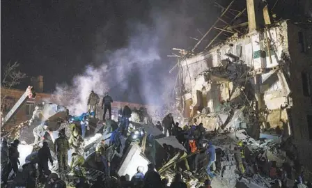  ?? YEVGEN HONCHARENK­O AP ?? Emergency workers and residents clear rubble early today after a Russian rocket hit an apartment building in Kramatorsk, Ukraine.