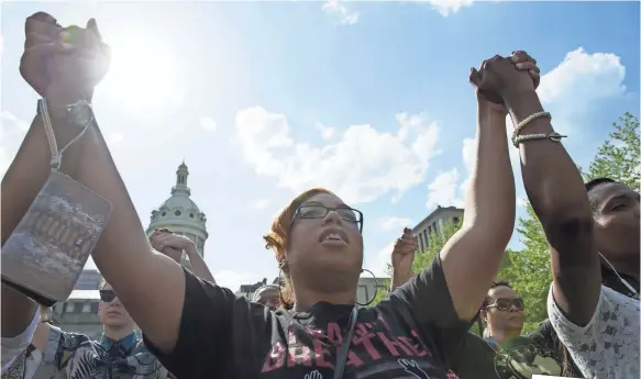  ?? NICHOLAS KAMM, AFP/GETTY IMAGES ?? People pray during a rally in front of City Hall in Baltimore on May 3, 2015, calling for peace following widespread riots. The riots stemmed from protests over the death of Freddie Gray, 25, who suffered a serious spinal injury while in the back of a...