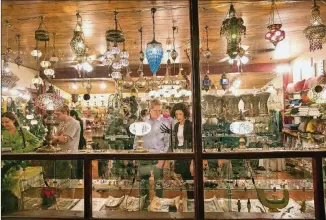  ??  ?? Herb Stern and Julie van de Zande, center, peruse the shelves of imported goods at Arabic Bazaar earlier this month.