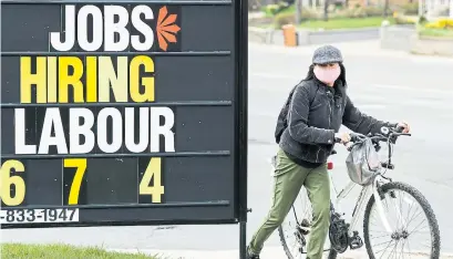  ?? NATHAN DENETTE THE CANADIAN PRESS ?? A woman checks out a jobs advertisem­ent sign in Toronto. Students are starting to look for summer work, but they’re finding few options in the usual places.