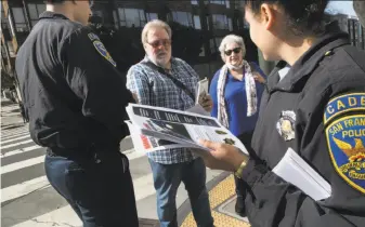  ?? Paul Kuroda / Special to The Chronicle ?? David and Vicki Woosey of the United Kingdom receive a flyer from San Francisco police cadets Ibrahem Abukhdeir and Sophia Abarca urging them to leave nothing in their cars.