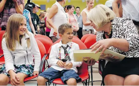  ?? DAVID KAWAI/OTTAWA CITIZEN ?? Ontario Health Minister Deb Matthews looks at a baby photo album with Ethan Peters and his sister Sheridan. The album shows the various stages of his treatment for severe combined immune deficiency, which is often fatal within the first few months of...