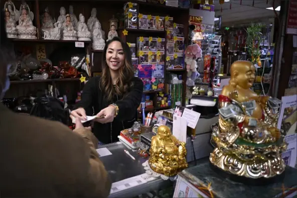  ?? HYOUNG CHANG — THE DENVER POST ?? Mimi Luong, co-owner of Truong An Gifts, works at the cashier of the gift store of Far East Center in Denver on November 9.