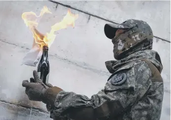  ?? ?? A local resident prepares to use a Molotov cocktail against a wall during a Ukrainian training campaign.