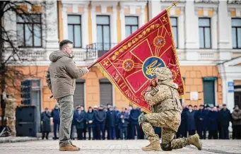  ?? Associated Press ?? Ukrainian President Volodymyr Zelenskyy, left, holds the flag of a military unit as an officer kisses it, during an event Friday commemorat­ing the first anniversar­y of the war.