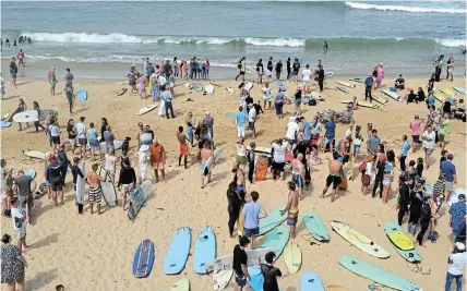  ?? ?? LOVING TRIBUTE: Surfers and members of the public move along the shoreline at Kelly’s Beach before the start of the paddle out ceremony for Dave Macgregor.