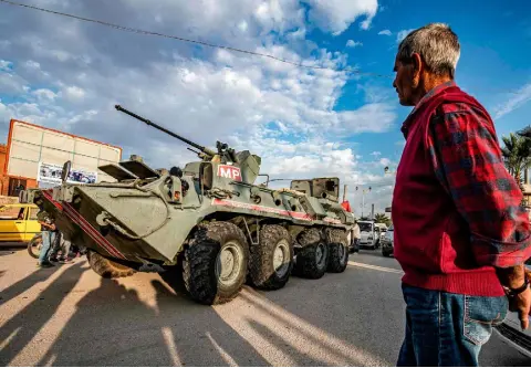  ??  ?? FLASHPOINT: A man watches as a Russian military police armoured vehicle passes through a street in northeast Syria, as part of a joint patrol between Russian forces and Syrian Kurdish Asayish internal security forces near the border with Turkey