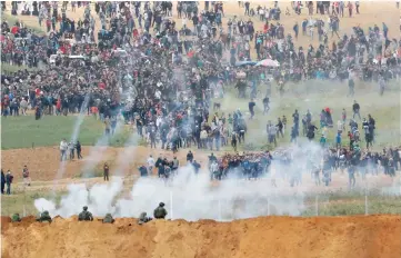  ??  ?? A picture taken from the southern Israeli kibbutz of Nahal Oz across the border from the Gaza strip shows tear gas grenades falling during a Palestinia­n tent city protest commemorat­ing Land Day, with Israeli soldiers seen below in the foreground. — AFP...
