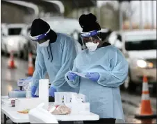  ?? JOHN RUCOSKY/TRIBUNE-DEMOCRAT VIA AP ?? Quamea Richards, left, and Tawanna Thomas of AMI Health, prepare for a long line of patients at a driveup COVID-19 testing facility at the Georgian Place in Somerset, Pa., Monday, Jan. 4.