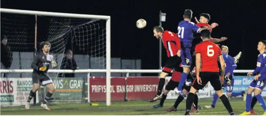  ?? Richard Birch ?? Bangor City’s Mike Williams (no.21) rises above the Prestatyn defence to head home the first goal of the match last Friday night.