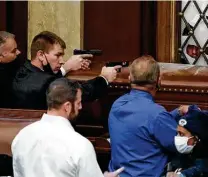  ?? J. Scott Applewhite / Associated Press ?? Capitol Police officers with guns drawn watch as a mob attempts to break into the House Chamber. Congress was quickly recessed during the attack.