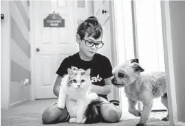  ??  ?? Carson Siegmeier, a second grade student with autism, plays with family cat Snowball. His mother obtained a doctor’s note to prevent him from being put in isolated timeout.