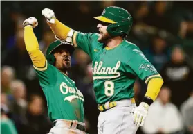  ?? Steph Chambers / Getty Images ?? Jed Lowrie (8), the only switch-hitter on the A’s active roster, celebrates with Tony Kemp after hitting a two-run home run during the fifth inning against the Mariners at T-Mobile Park in Seattle on Tuesday.