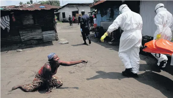  ?? John Moore ?? > A woman throws a handful of soil towards the body of her sister as an Ebola burial team takes her away