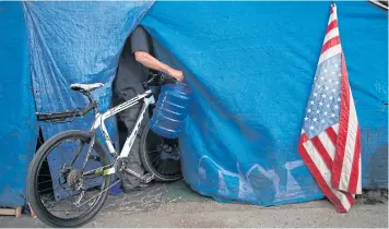  ??  ?? FLAGGING INEQUALITY: A tent pitched on the Santa Ana River trail as a homeless man enters the tent in Anaheim, California.