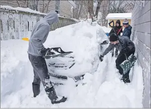  ?? CP PHOTO ?? Boys dig a car out of the snow in Halifax on Tuesday following a major winter storm that hit the Maritimes.