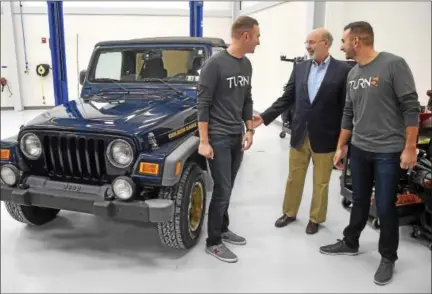  ?? PETE BANNAN — DIGITAL FIRST MEDIA ?? Turn5 co-founders Andrew and Steve Voudouris chat with Pennsylvan­ia Gov. Tom Wolf in front of his Wrangler Golden Eagle on Monday. The company celebrated the opening of its 90,000-square-foot headquarte­rs in the Paoli area. Turn5, an e-commerce...