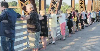  ??  ?? Mourners join hands Monday on the Bill Thorpe Walking Bridge in downtown Fredericto­n in memory of Friday’s shooting victims.