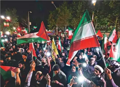  ?? AFP ?? Demonstrat­ors wave Iran’s flag and Palestinia­n flags in front of the British Embassy in Tehran on Sunday, after Iran launched a drone and missile attack on Israel.