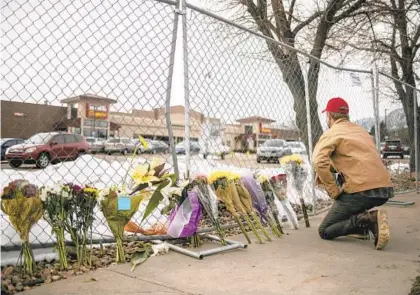  ?? CHET STRANGE/GETTY ?? A mourner leaves flowers and pays tribute Tuesday morning after a gunman opened fire at a King Sooper’s grocery store Monday in Boulder, Colorado. Ten people were killed in the attack.
