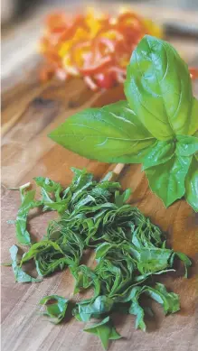  ?? LUCY HERRMAN ?? Chiffonade the basil into thin strips.