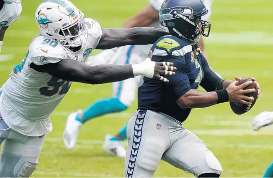  ?? LYNNE SLADKY/AP ?? Dolphins defensive end Shaq Lawson, left, grabs Seahawks quarterbac­k Russell Wilson during a game on Oct. 4 in Miami Gardens.